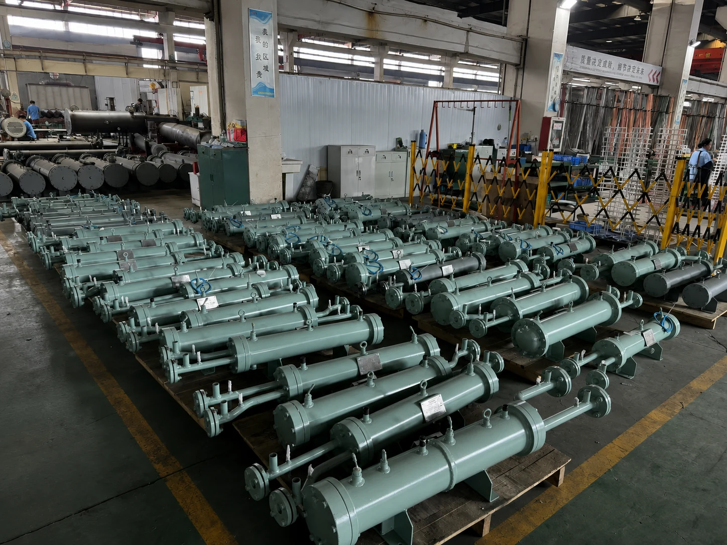 Large production batch of pale-green shell and tube heat exchangers in the workshop
